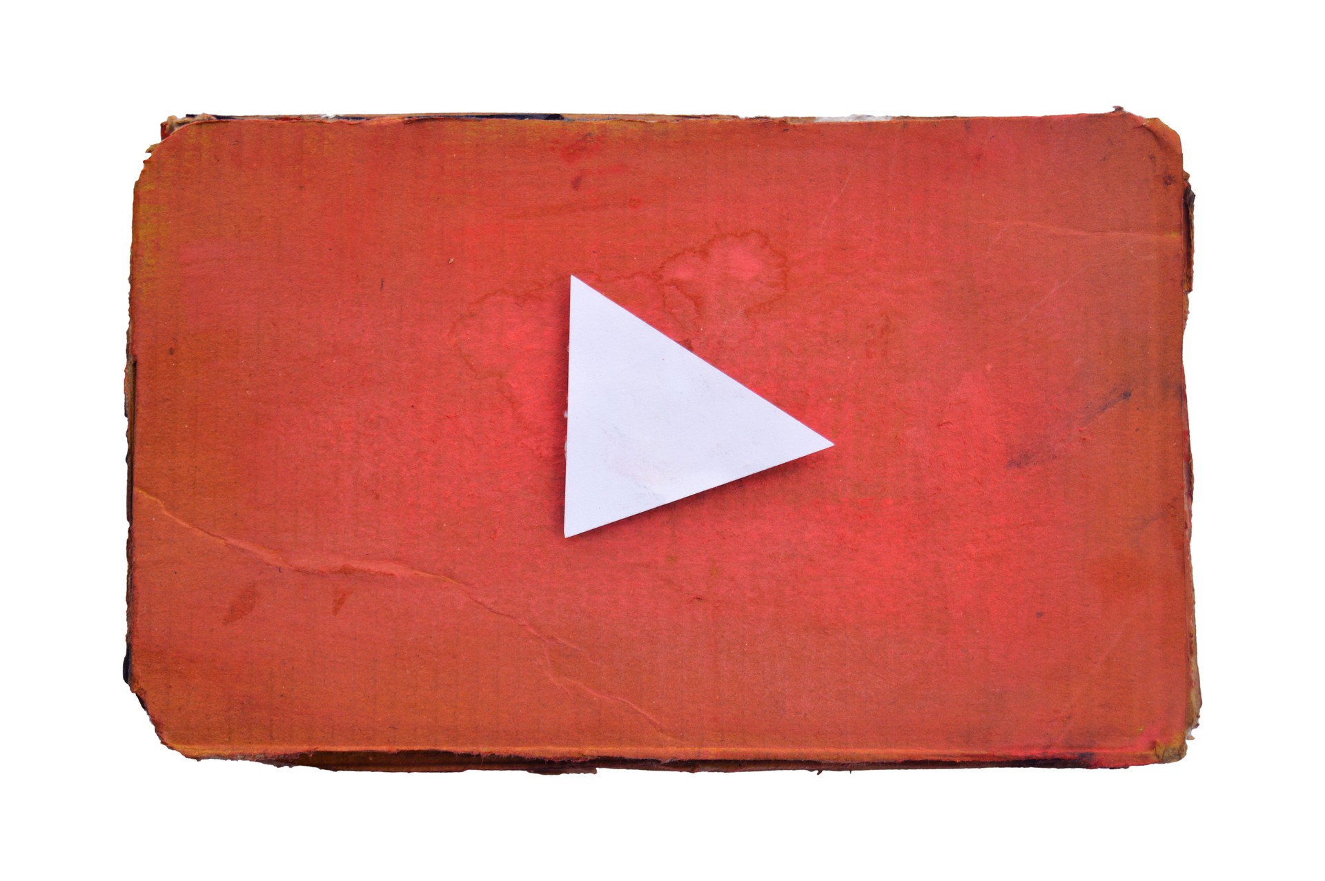 Cut out of white paper cut as triangle like Play button icon symbol on faded red corrugated painted old weathered distressed ruined damaged horizontal cardboard  background